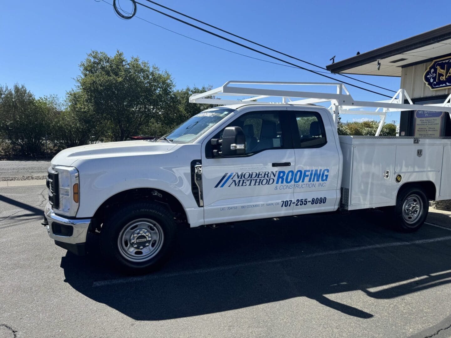 White roofing company truck parked outside building.