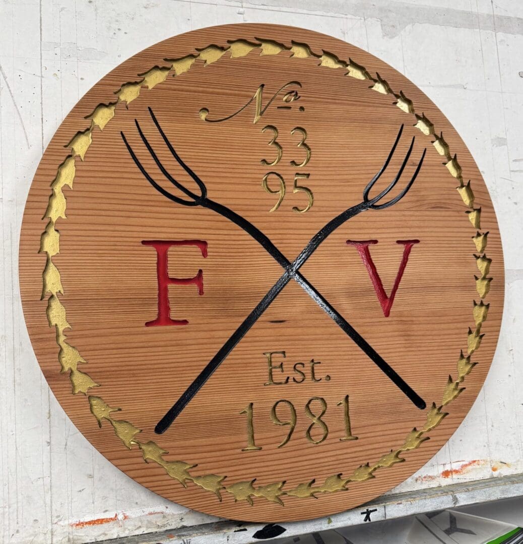 Wooden plaque with pitchforks and initials.