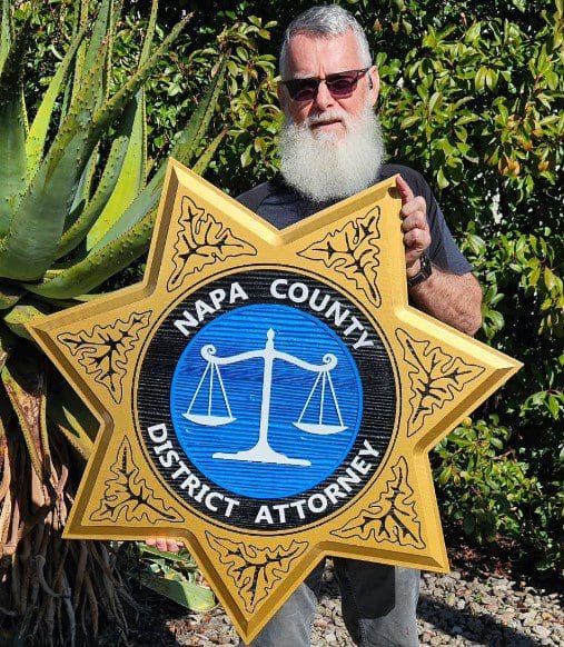 Napa County District Attorney Sandblast redwood Man holding Napa County District Attorney sign.